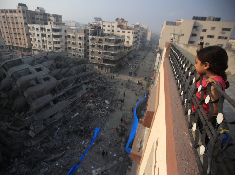 2024 Una niña palestina observa desde lo alto de un edificio la destrucción de una torre residencial bombardeada por aviones de guerra israelíes. Consta de diez plantas y alberga a 70 familias . ©Mohammed Zaanoun